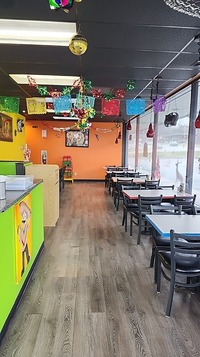 The colorful dining room at Taqueria Roly's, hung with papel picado banners over warm orange and yellow walls