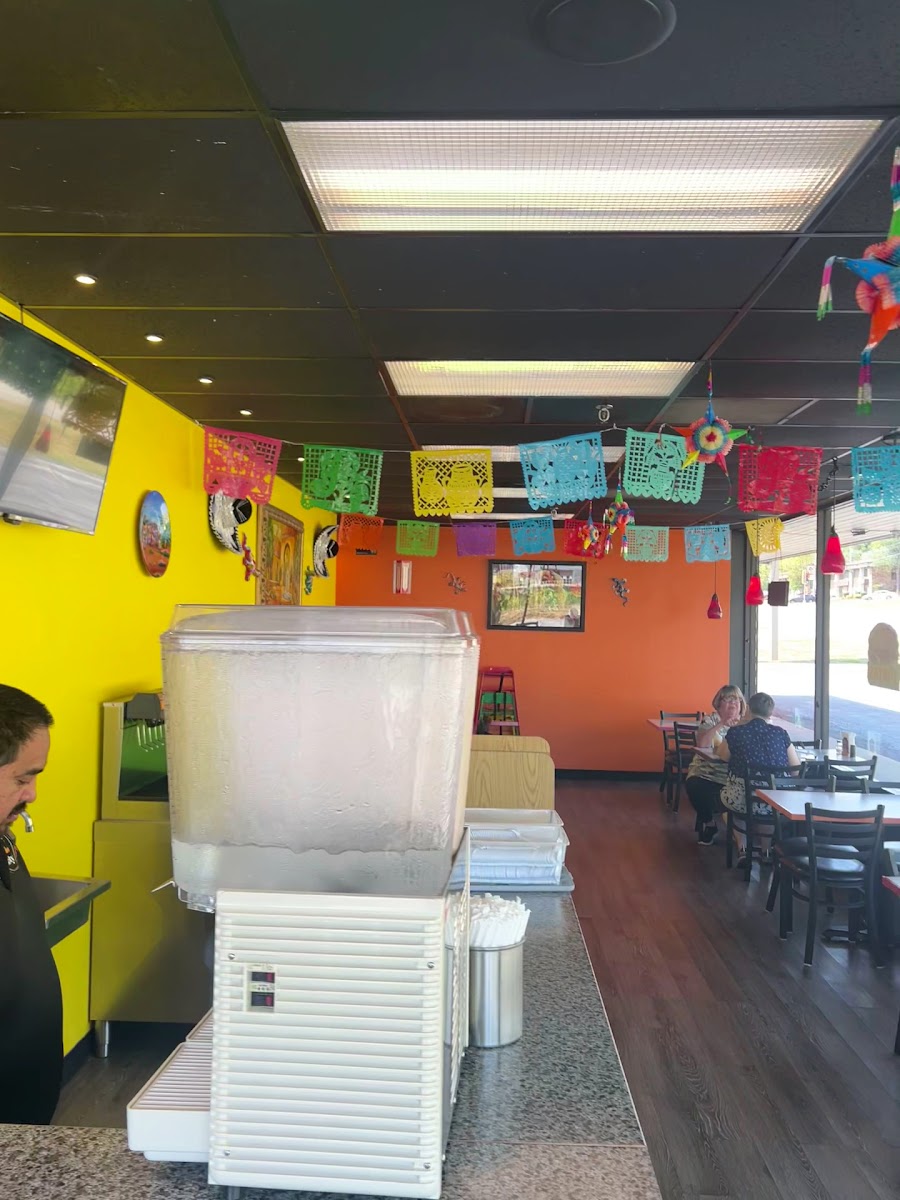 The counter and dining room with papel picado and an agua fresca dispenser
