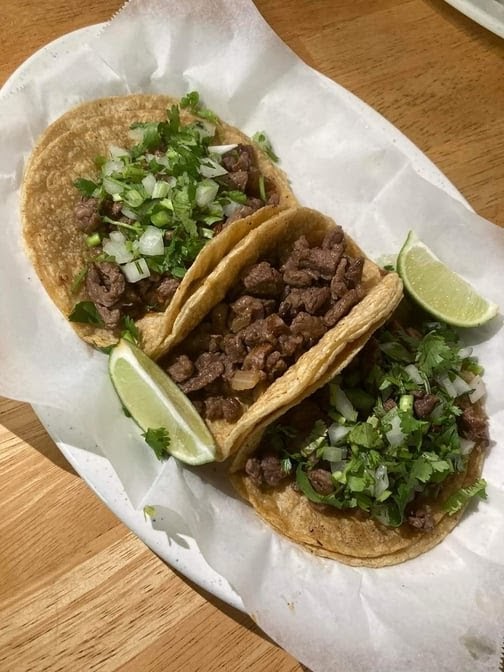 Carne asada tacos on handmade corn tortillas, topped with cilantro, onion and a wedge of lime