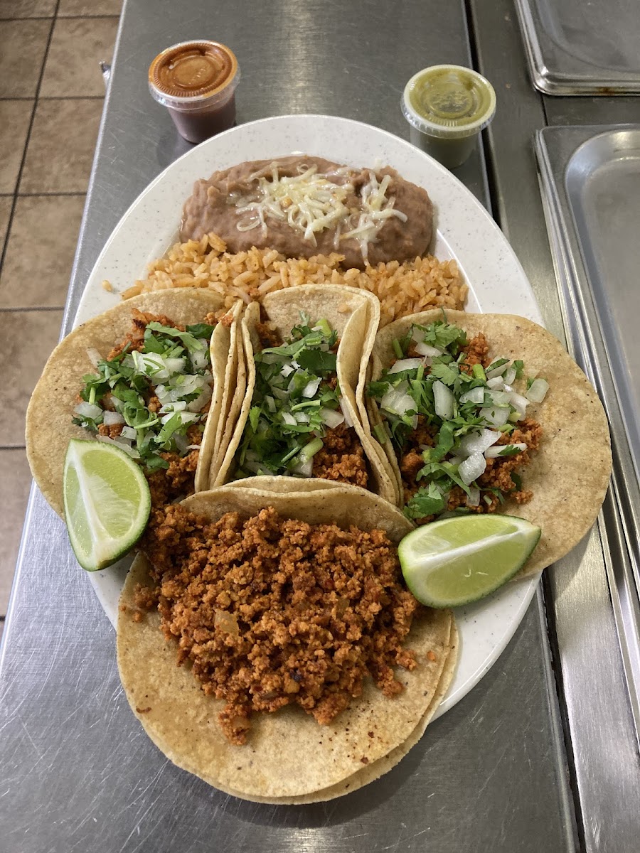 A taco plate at Taqueria Roly's with three street tacos, refried beans, Mexican rice and two salsas