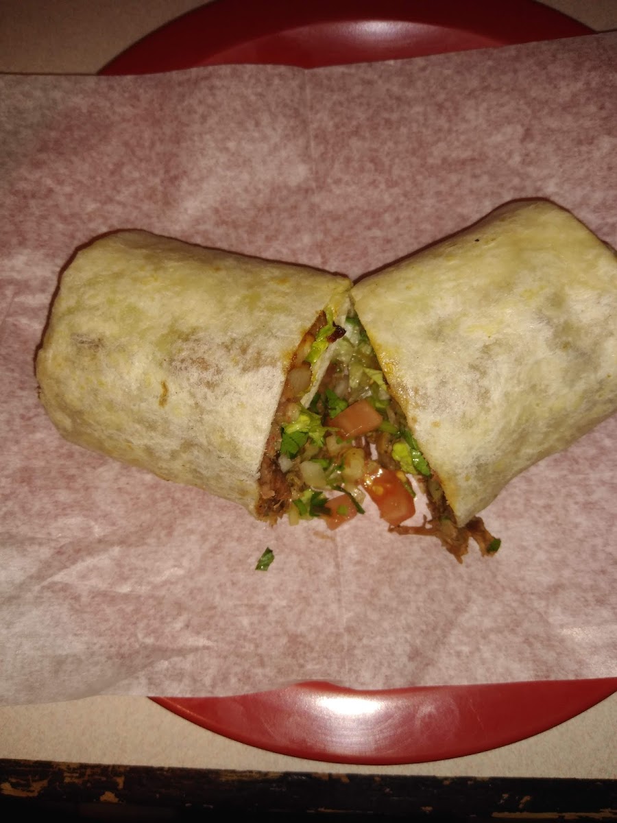 A steak burrito cut in half, showing the filling of asada, pico and avocado
