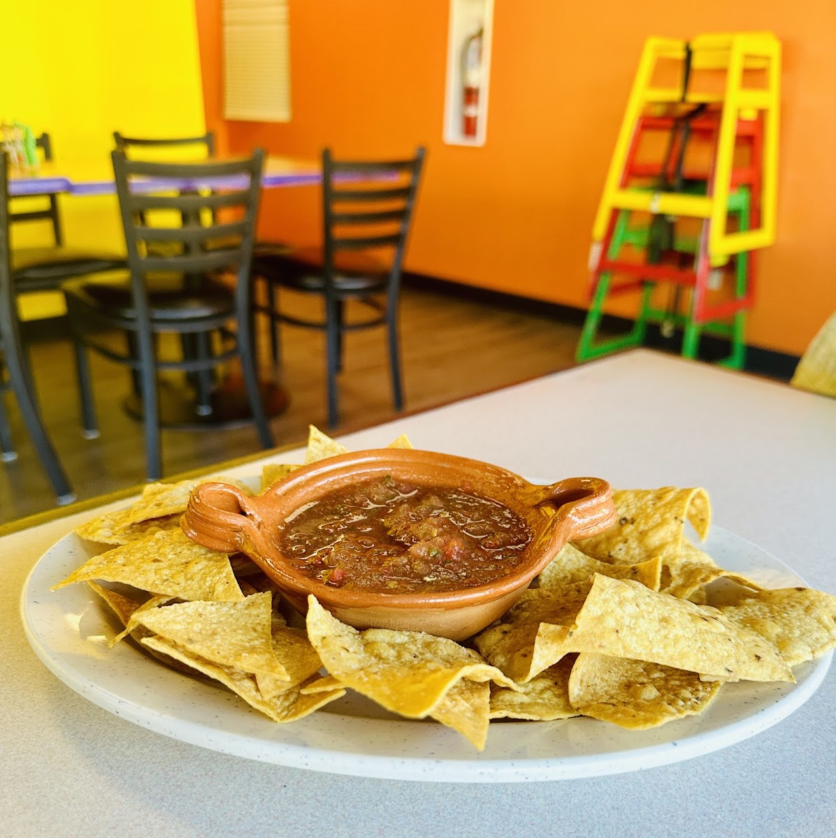 Chips and red salsa in a clay bowl in the bright dining room